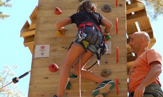  fille escaladant un mur d'escalade à côté d'un moniteur 